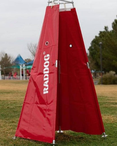 RADDOG escape blind in red vinyl with rear opening door, set up outdoors on a field, designed for IGP protection training and decoy movement.